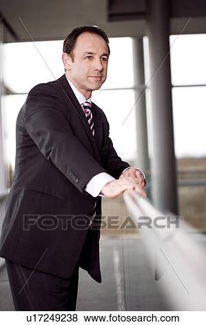 Stock Photo - Businessman standing on walkway in office building. Fotosearch