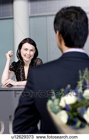 Businessman with bouquet of flowers being greeted by office receptionist View Large Photo Image Stock Image - Businessman with bouquet of flowers being greeted by office receptionist. Fotosearch