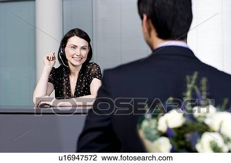Businessman with bouquet of flowers being greeted by office receptionist View Large Photo Image Stock Image - Businessman with bouquet of flowers being greeted by office receptionist. Fotosearch