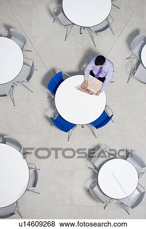 Stock Photo - Businessman working on laptop at table of office canteen. Fotosearch