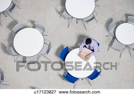 Stock Photo - Businessman working on laptop at table of office canteen. Fotosearch