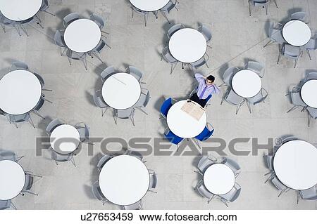 Stock Photo - Businessman working on laptop at table of office canteen. Fotosearch