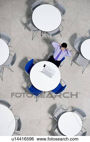 Stock Photograph - Businessman working on laptop at table of office canteen. Fotosearch