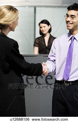 Stock Photograph - Businesswoman being greeted at office reception. Fotosearch