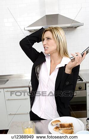 Businesswoman having breakfast in the kitchen and talking on the phone View Large Photo Image Stock Photo - Businesswoman having breakfast in the kitchen and talking on the phone. Fotosearch