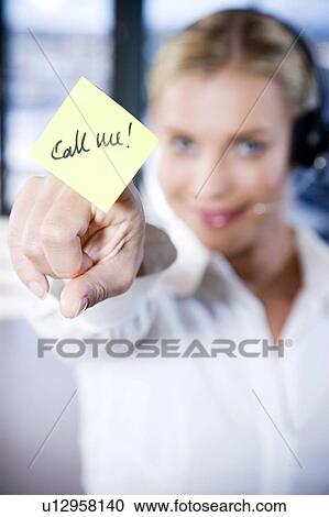 Stock Image - Businesswoman in a call centre with a sticky note saying Call Me. Fotosearch