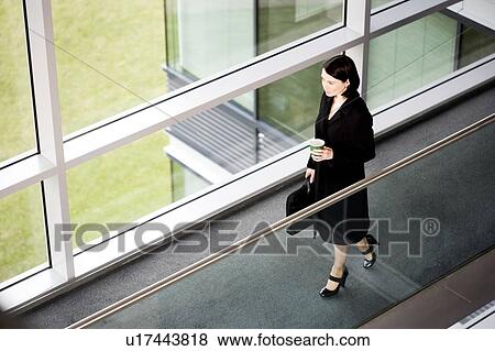 Stock Photo - Businesswoman in modern office building, arriving for work. Fotosearch