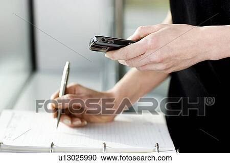 Stock Image - Businesswoman or secretary making an appointment in a diary. Fotosearch