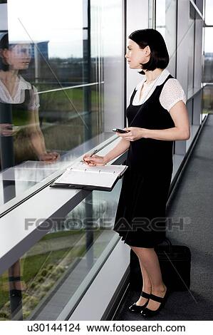 Businesswoman or secretary with an appointments diary, staring out of the window View Large Photo Image Picture - Businesswoman or secretary with an appointments diary, staring out of the window. Fotosearch
