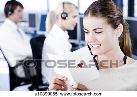 Stock Photography - Businesswoman reading her valentines card in an office. Fotosearch