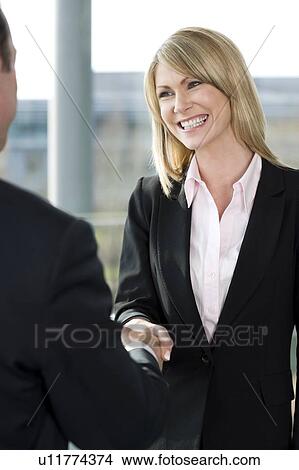 Businesswoman shaking hands with male client or colleague View Large Photo Image Picture - Businesswoman shaking hands with male client or colleague. Fotosearch