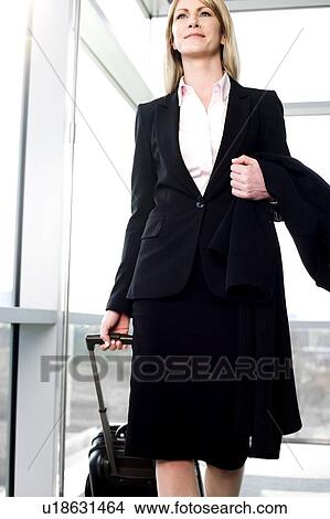 Businesswoman traveling, pulling suitcase along inside station or airport View Large Photo Image Picture - Businesswoman traveling, pulling suitcase along inside station or airport. Fotosearch