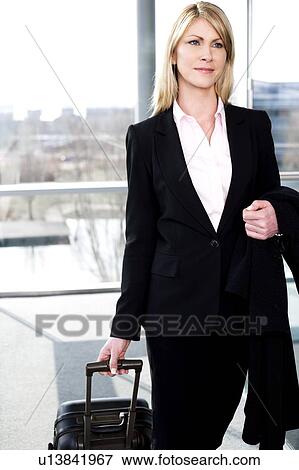 Businesswoman traveling, pulling suitcase along inside station or airport View Large Photo Image Stock Photo - Businesswoman traveling, pulling suitcase along inside station or airport. Fotosearch