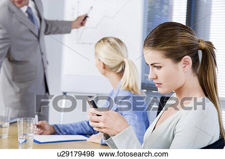 Businesswoman using a PDA during a presentation View Large Photo Image Stock Photo - Businesswoman using a PDA during a presentation. Fotosearch