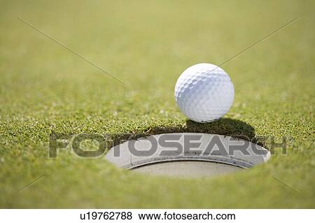 Close-up of a golf ball on the edge of a hole View Large Photo Image Stock Photo - Close-up of a golf ball on the edge of a hole. Fotosearch