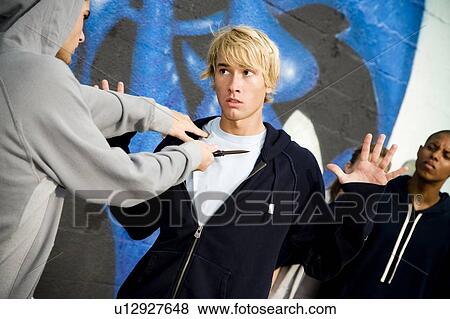 Stock Photo - Confrontation between two young men and a group of friends in front of a graffiti covered wall . Fotosearch