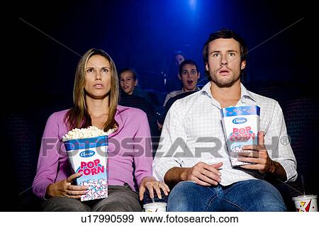 Stock Photo - Couple at the cinema watching a shocking film. Fotosearch