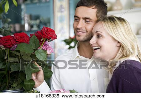 Stock Photography - Couple choosing flowers in a florist's shop, red roses. Fotosearch