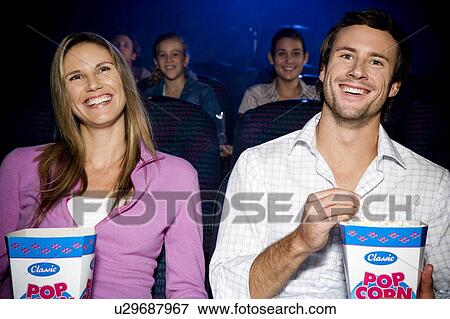 Couple enjoying a film at the cinema View Large Photo Image Stock Photo - Couple enjoying a film at the cinema. Fotosearch