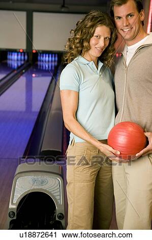 Couple in a bowling alley holding a red bowling ball View Large Photo Image Stock Image - Couple in a bowling alley holding a red bowling ball. Fotosearch