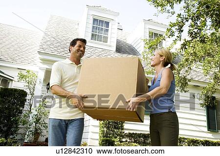 Couple moving into their new home, carrying a packing box View Large Photo Image Stock Image - Couple moving into their new home, carrying a packing box. Fotosearch