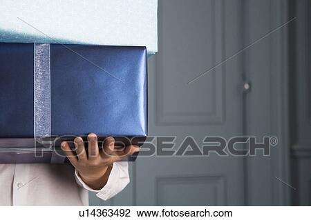 Stock Image - cropped image of boy carrying presents. Fotosearch