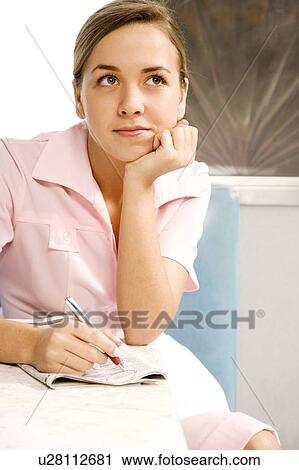 Stock Image - Diner waitress daydreaming whilst looking at the classified section of a newspaper. Fotosearch