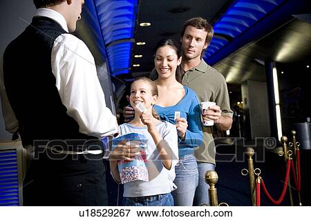 Stock Photo - Family at the cinema handing tickets to the usher. Fotosearch