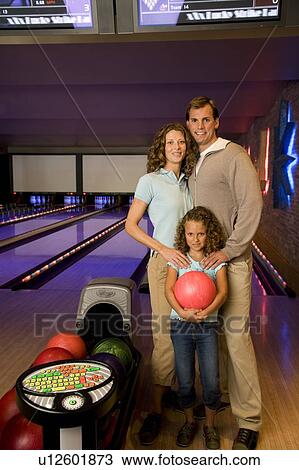 Family in a bowling alley, daughter holding a red bowling ball View Large Photo Image Stock Image - Family in a bowling alley, daughter holding a red bowling ball. Fotosearch