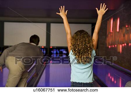 Stock Image - Father and daughter in a bowling alley, celebrating victory. Fotosearch