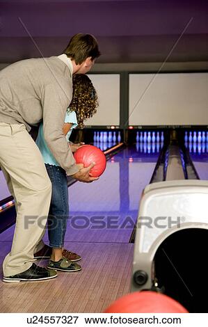 Stock Photo - Father and daughter in a bowling alley, about to roll the ball. Fotosearch