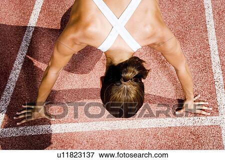 Stock Photo - Female athlete in the starting blocks. Fotosearch