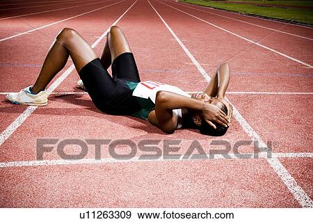 Stock Photo - Female athlete resting on a running track. Fotosearch