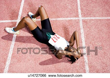 Stock Photograph - Female athlete resting on a running track. Fotosearch