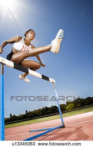 Female hurdler in action View Large Photo Image Stock Image - Female hurdler in action. Fotosearch