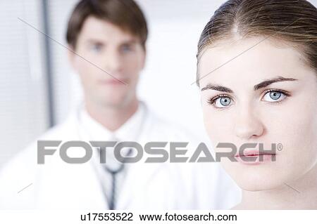 Stock Image - Female with male doctor out of focus in backgroundnn. Fotosearch