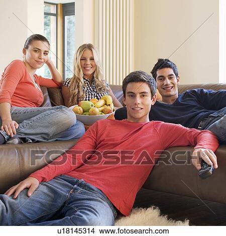 Picture - Four teenage friends watching television. Fotosearch