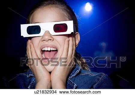 Picture - Girl at the cinema watching a film through 3-D glasses. Fotosearch