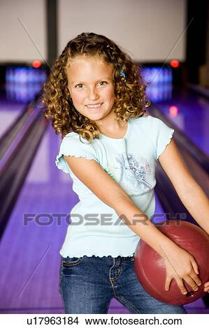 Picture - Girl in a bowling alley holding a red bowling ball. Fotosearch