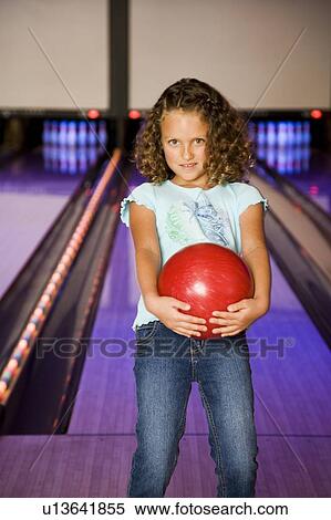 Stock Photography - Girl in a bowling alley holding a red bowling ball. Fotosearch