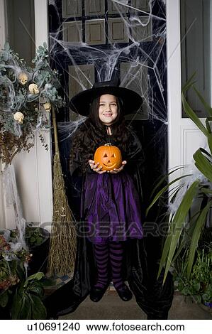 Girl in a witch's costume at a Hallowe'en party, holding a pumpkin View Large Photo Image Stock Image - Girl in a witch's costume at a Hallowe'en party, holding a pumpkin . Fotosearch