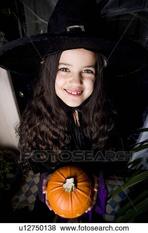 Girl in a witch's costume at a Hallowe'en party, holding a pumpkin View Large Photo Image Stock Photo - Girl in a witch's costume at a Hallowe'en party, holding a pumpkin . Fotosearch