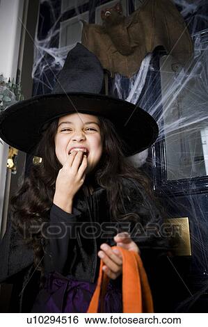 Girl in a witch's costume at a Hallowe'en party, eating sweets View Large Photo Image Stock Photograph - Girl in a witch's costume at a Hallowe'en party, eating sweets . Fotosearch