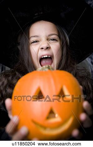 Girl in costume at a Hallowe'en party, holding a pumpkin with a carved face View Large Photo Image Picture - Girl in costume at a Hallowe'en party, holding a pumpkin with a carved face. Fotosearch