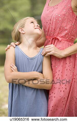 girl looking up at woman standing behind her View Large Photo Image Stock Photograph - girl looking up at woman standing behind her. Fotosearch