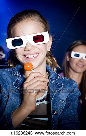 Girl with lollipop at the cinema watching a film through 3-D glasses View Large Photo Image Stock Image - Girl with lollipop at the cinema watching a film through 3-D glasses. Fotosearch