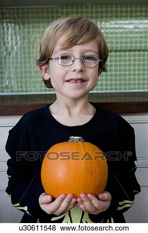 Stock Photo - Little boy holding an orange Hallowe'en pumpkin. Fotosearch