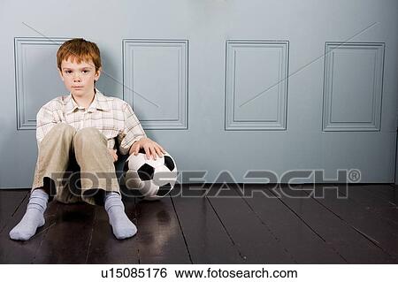 Stock Photograph - little boy sitting on floor with football. Fotosearch