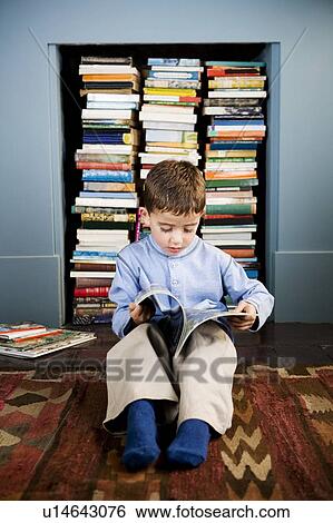 Stock Photograph - little boy sitting on the floor reading. Fotosearch