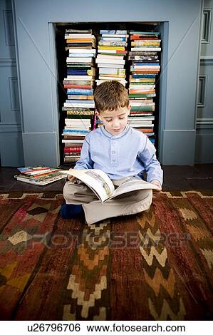 Stock Photograph - little boy sitting on the floor reading. Fotosearch
